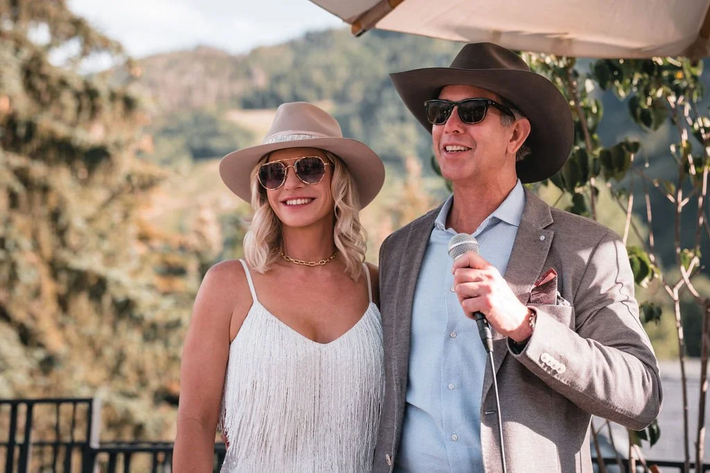 Two wedding guests in sun hats smiling outdoors