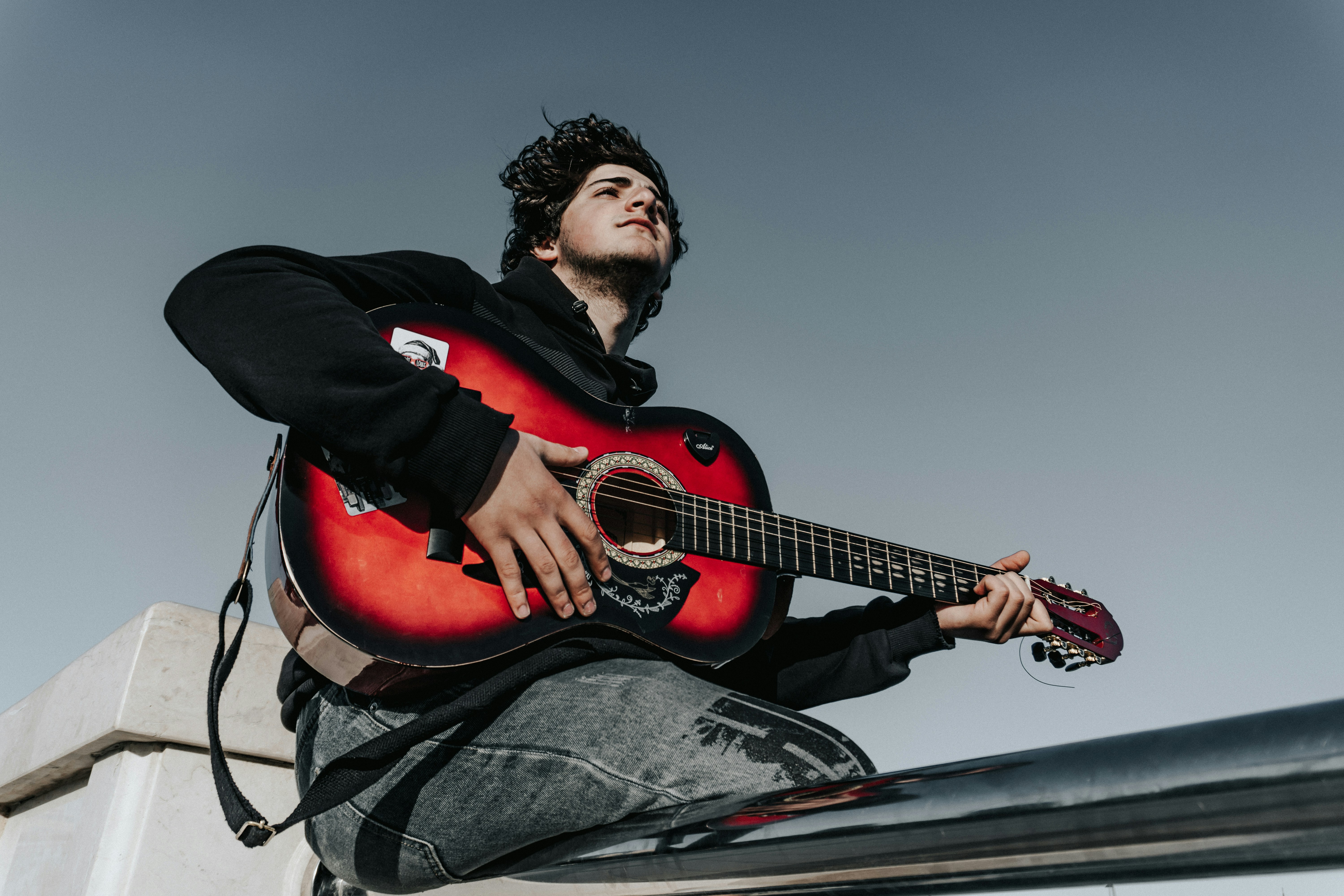 Man sitting on railing with acoustic guitar