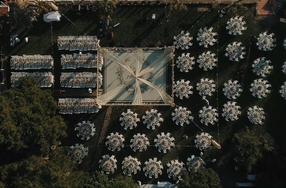 A couple dances closely, showcasing a flowing green dress, against a soft, blurred background of other guests.