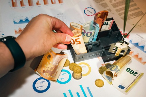 A person putting money into a miniature model house, illustrating a mortage