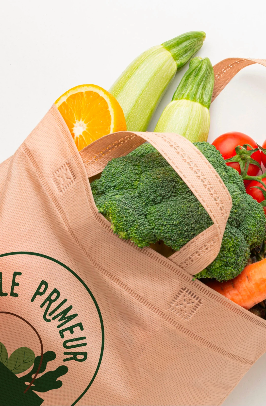 Mockup tote bag saumon avec le logo Le Primeur des Terroirs rempli de légumes frais — application de l'identité visuelle sur support textile, branding marché bio local, Tartelette Concept