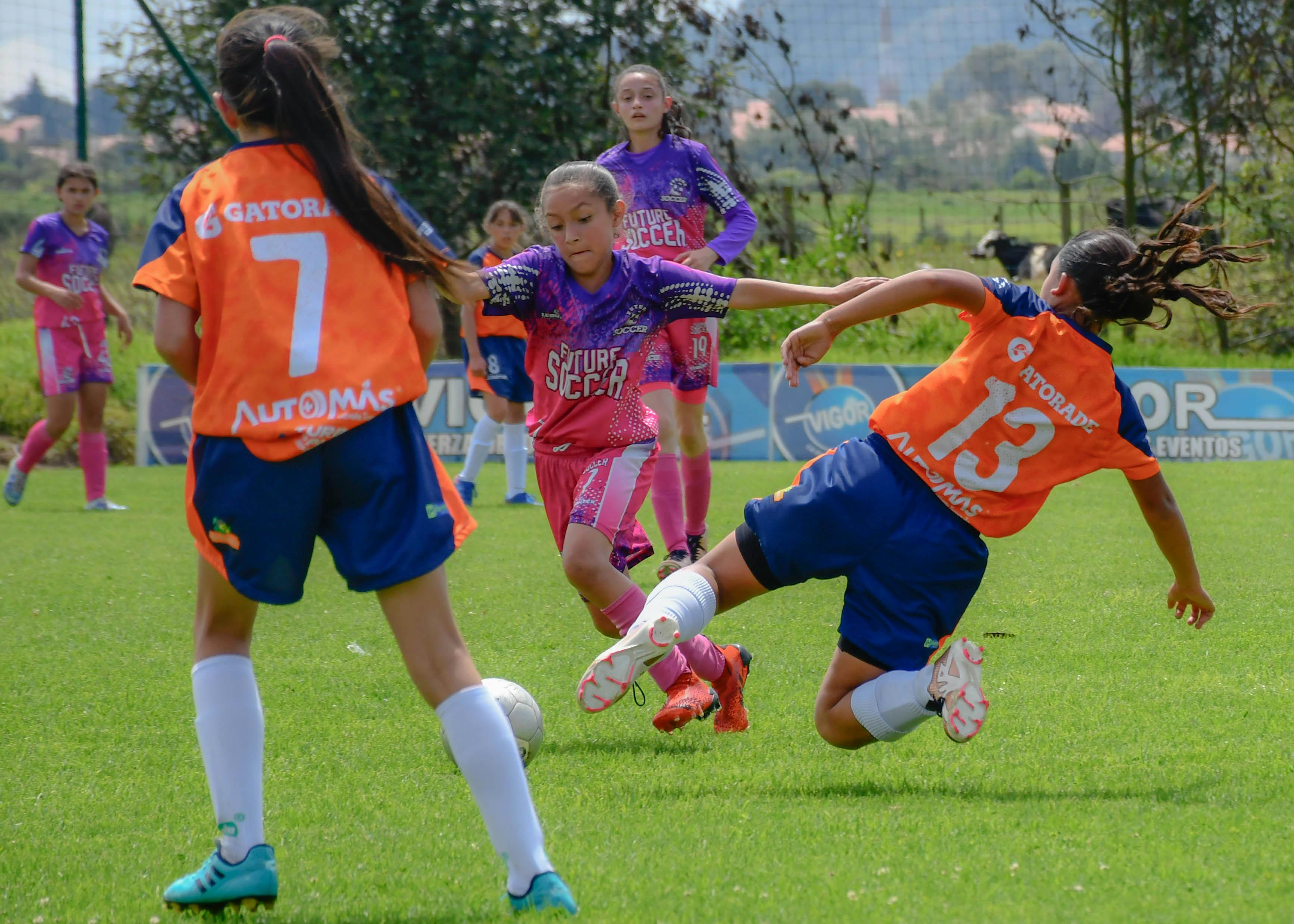 Two teen girls battling for the ball in a soccer game