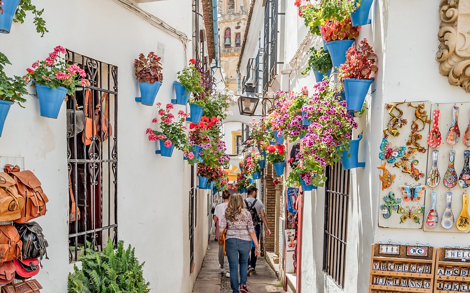 Enge Gasse im jüdischen Viertel von Córdoba mit bunten Blumen und Keramik an den Wänden.