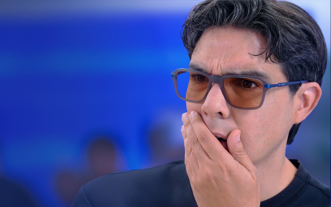 Close-up of beige and taupe-colored Slate Stride sneakers with dynamic curved sole design, worn with white socks and tan trousers, placed on a neutral-toned background.