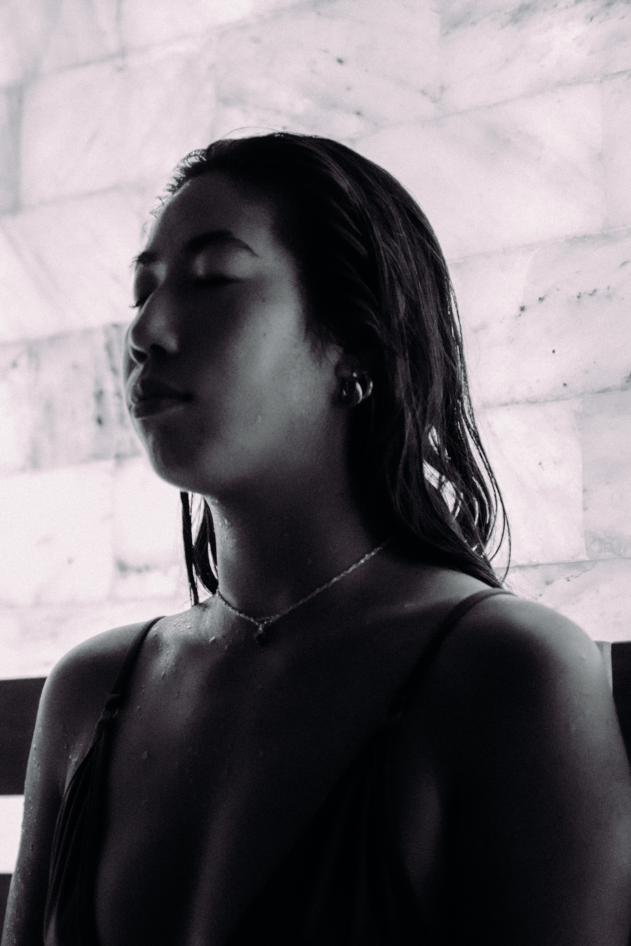 Black and white portrait of a person standing quietly with eyes closed against a marble wall during a silent practice