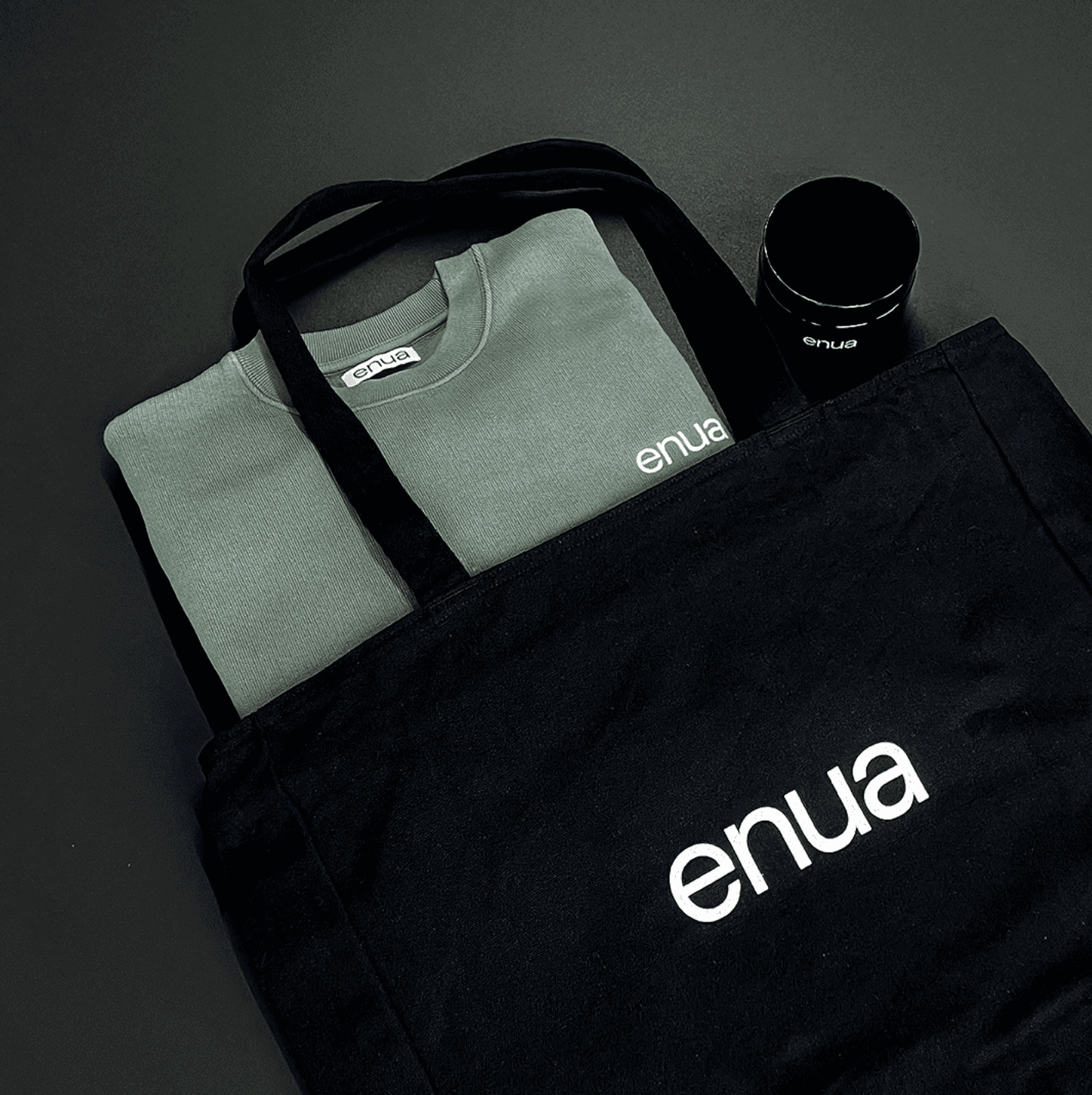 Foto einer enua Totebag mit einem Aufbewahrungsglas und einem grünen enua sweatshirt.