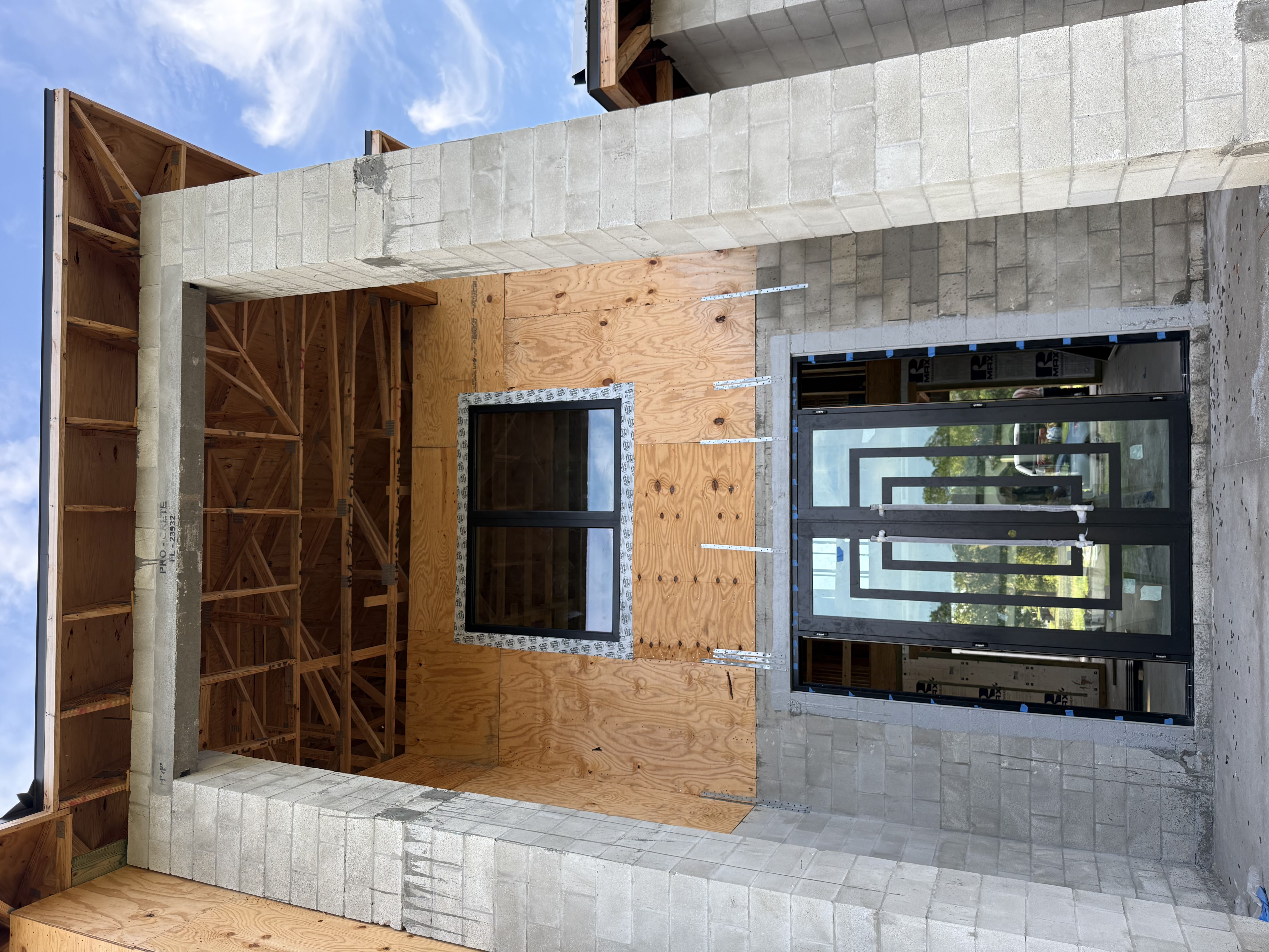 Modern glass double doors and a large window on a home under construction.
