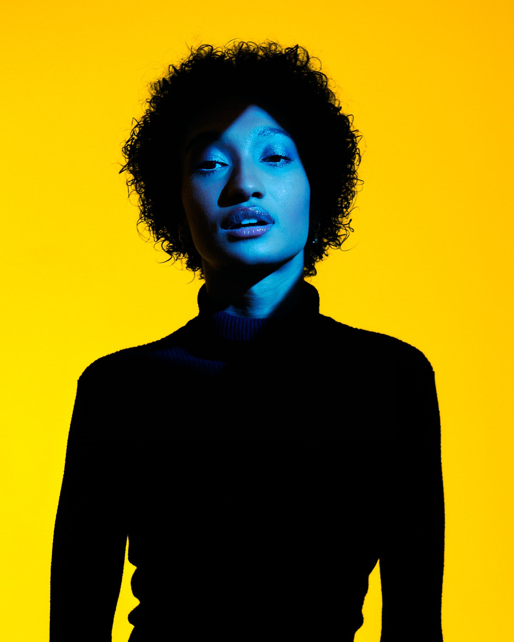 A model’s face and upper body are illuminated against a yellow background in Revelator Studio.