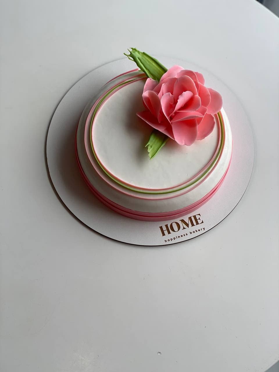 Elegant white mousse cake with pink fondant rose decoration on tiered base