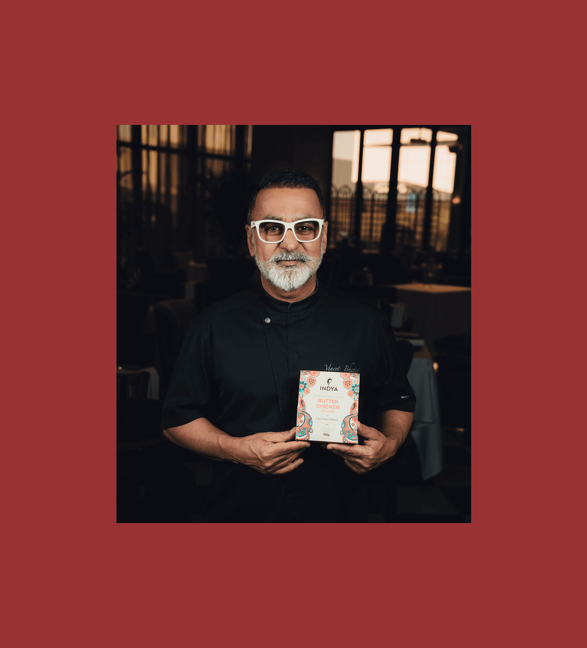 Chef Vineet Bhatia holding a pack of Indya Spices Butter Chicken blend. Celebrated Indian chef endorsing premium Indian spice mixes for authentic home-cooked flavors.