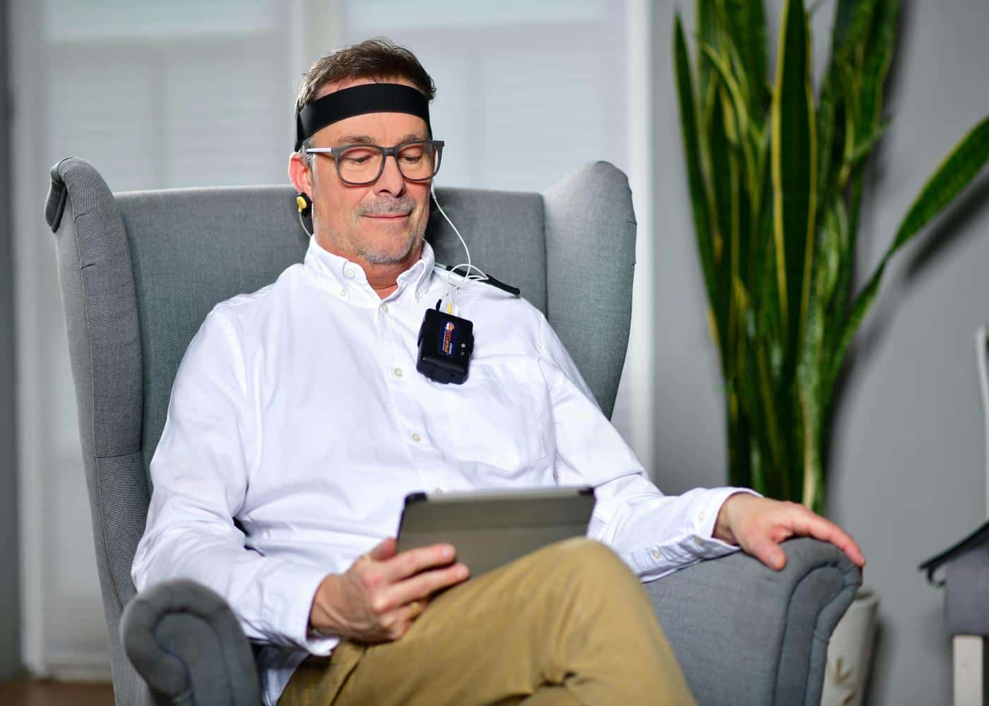 Man wearing a self-tracking eeg headband and looking at a tablet