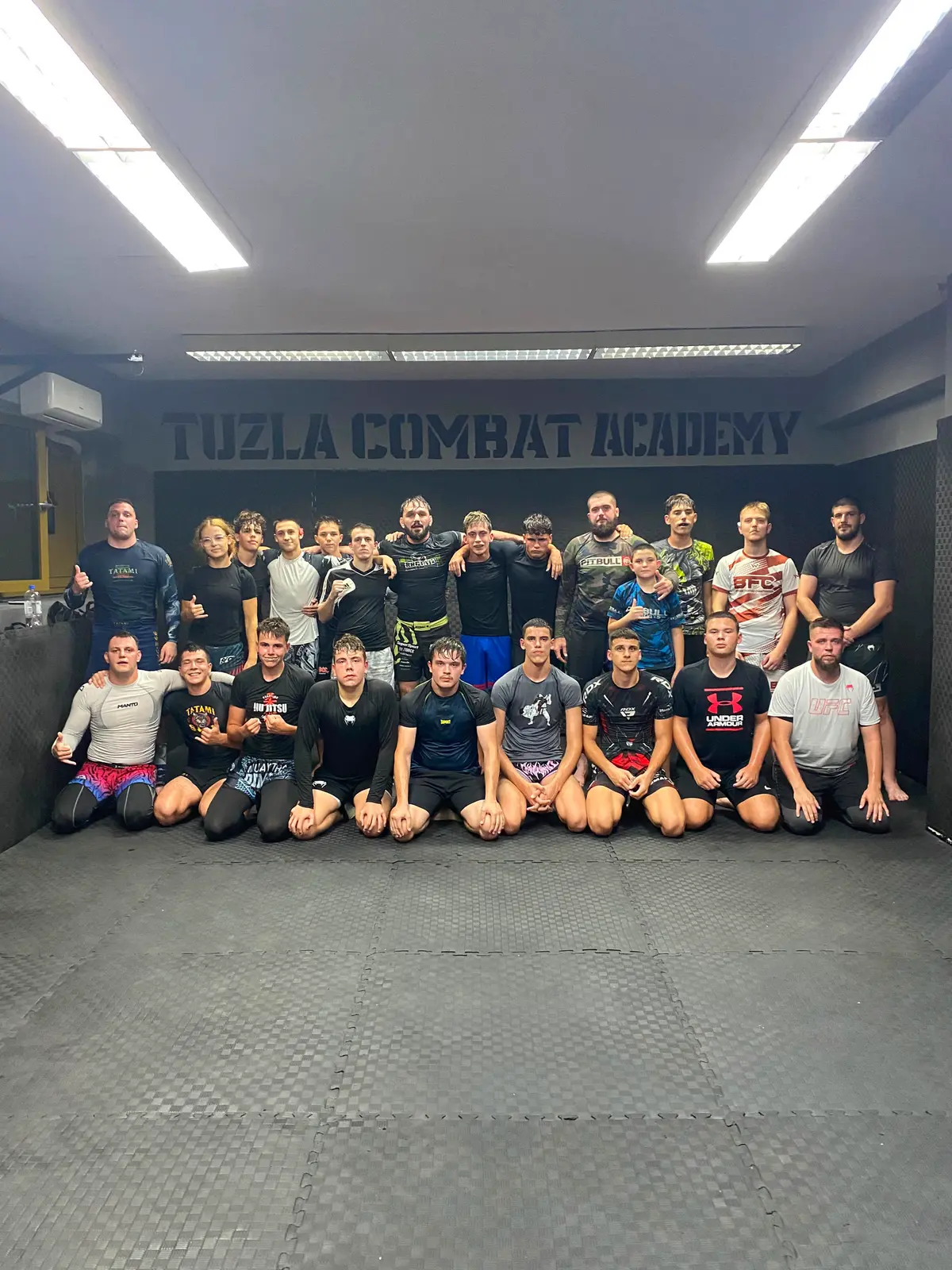 Članovi i treneri Tuzla Combat Academy pozicioniraju se za grupnu fotografiju u sali akademije.