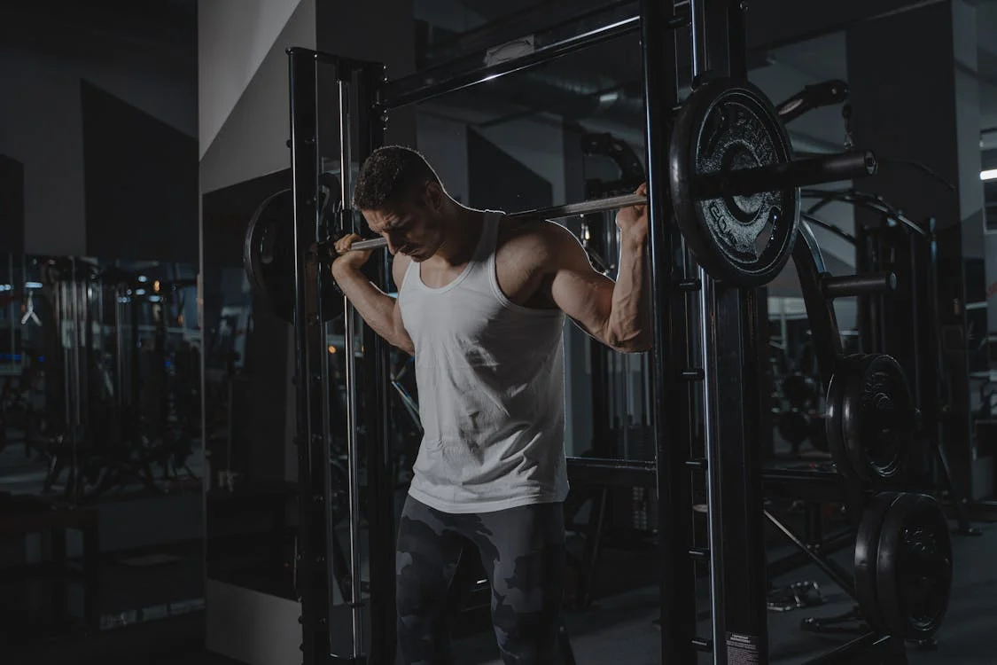 man performing high bar back squats using smith machine