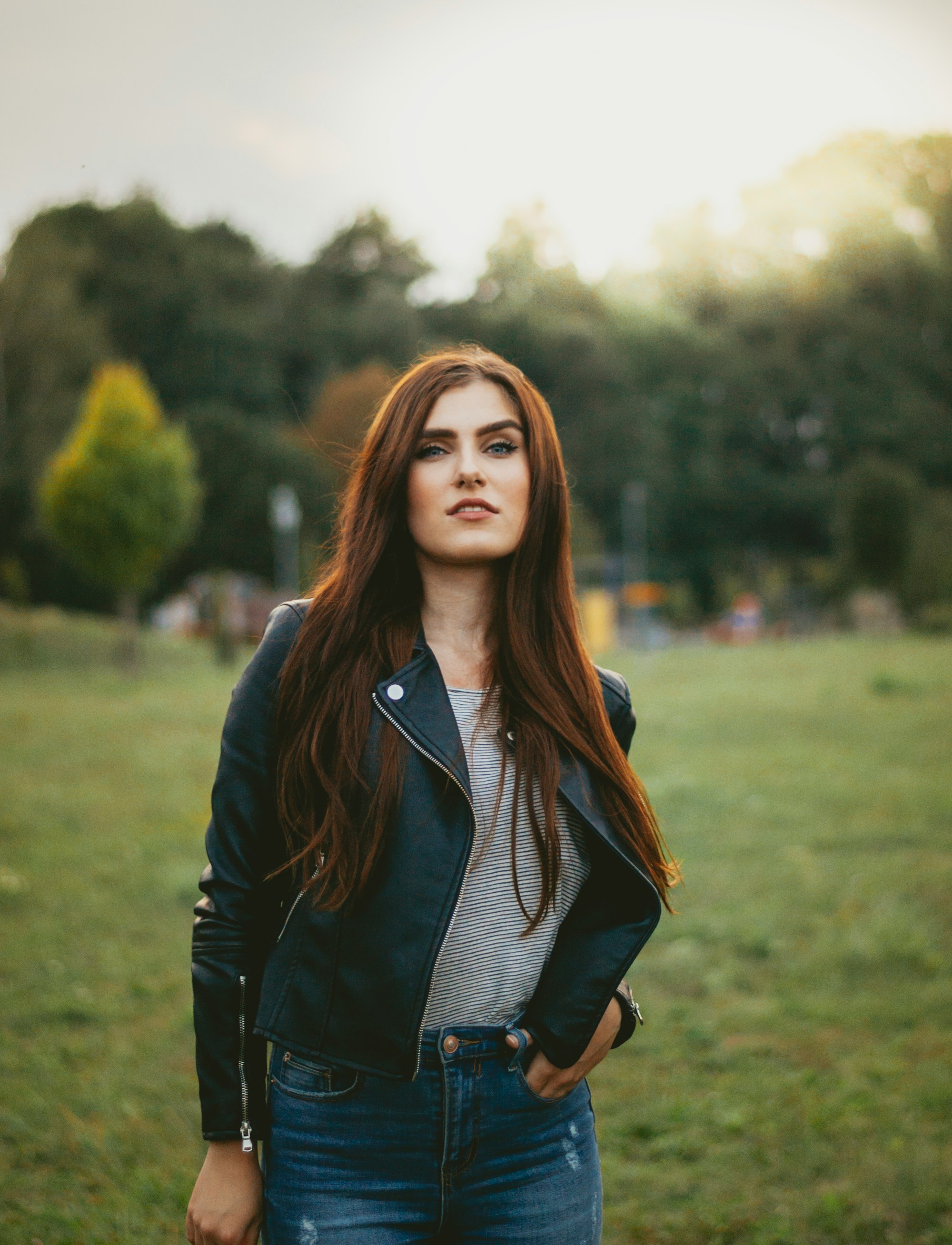 woman with hand on pocket standing on green grass field at daytime