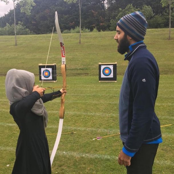 A Karima pupil learning archery with an instructor on a school trip