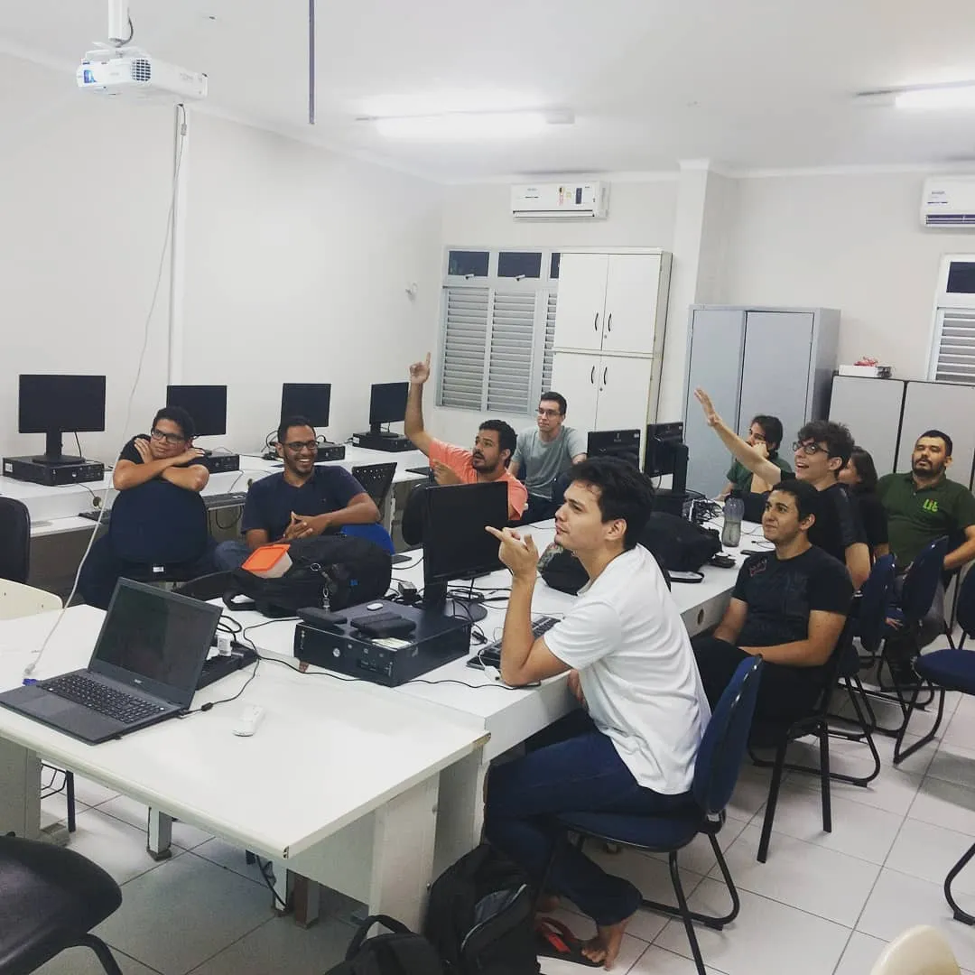 a group of men sitting at a table working on computers
