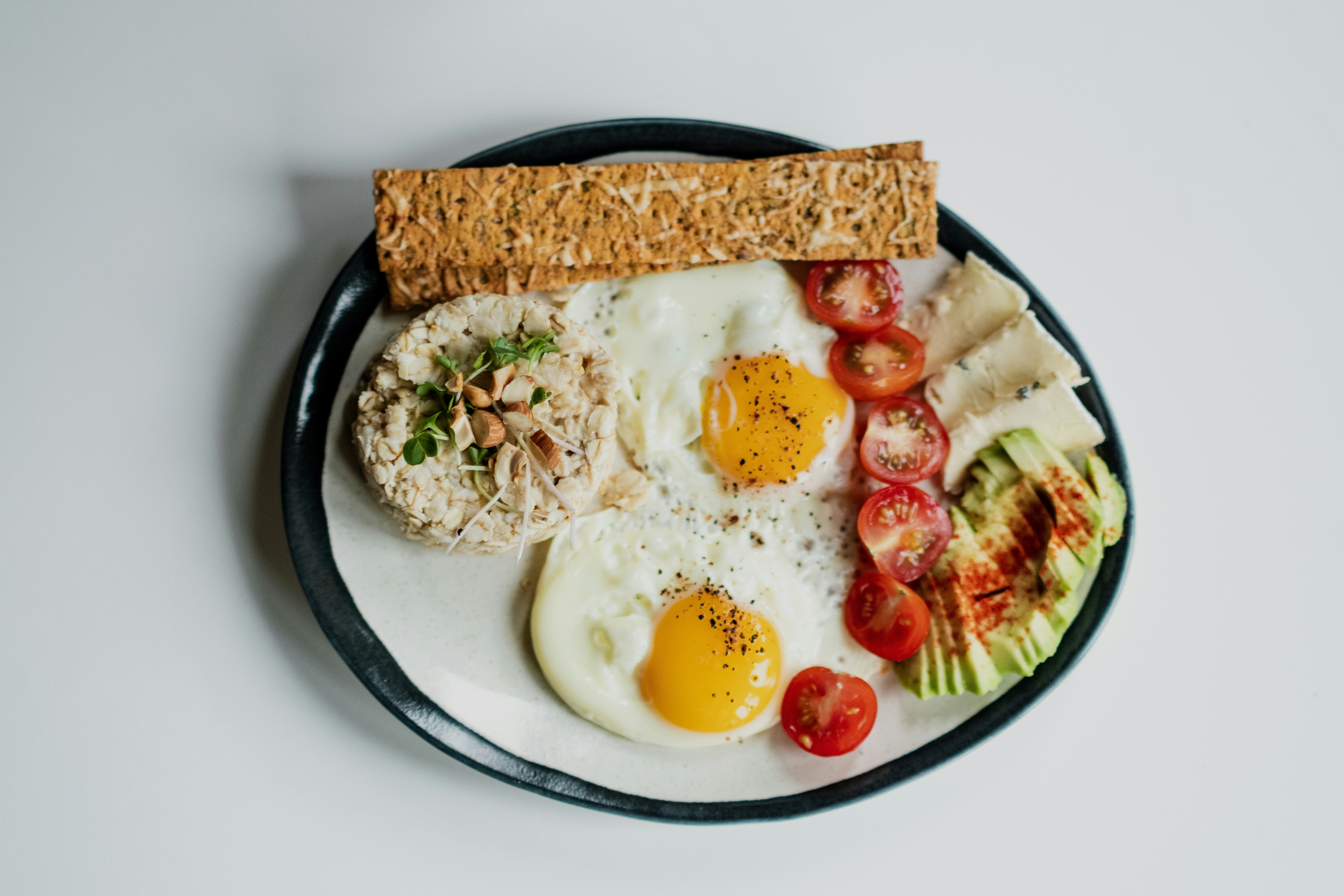 A plate of eggs with tomatoes, avocado and whole-grain bread, showing eggs as a naturally low-FODMAP protein for a SIBO diet