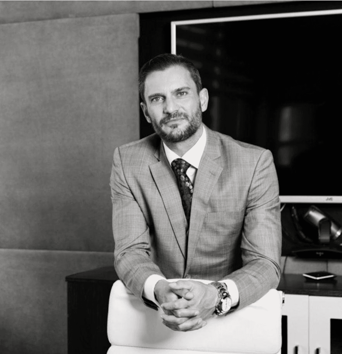Conrad Rheeder, founder of Issuer Group, seated in an office wearing a light suit.