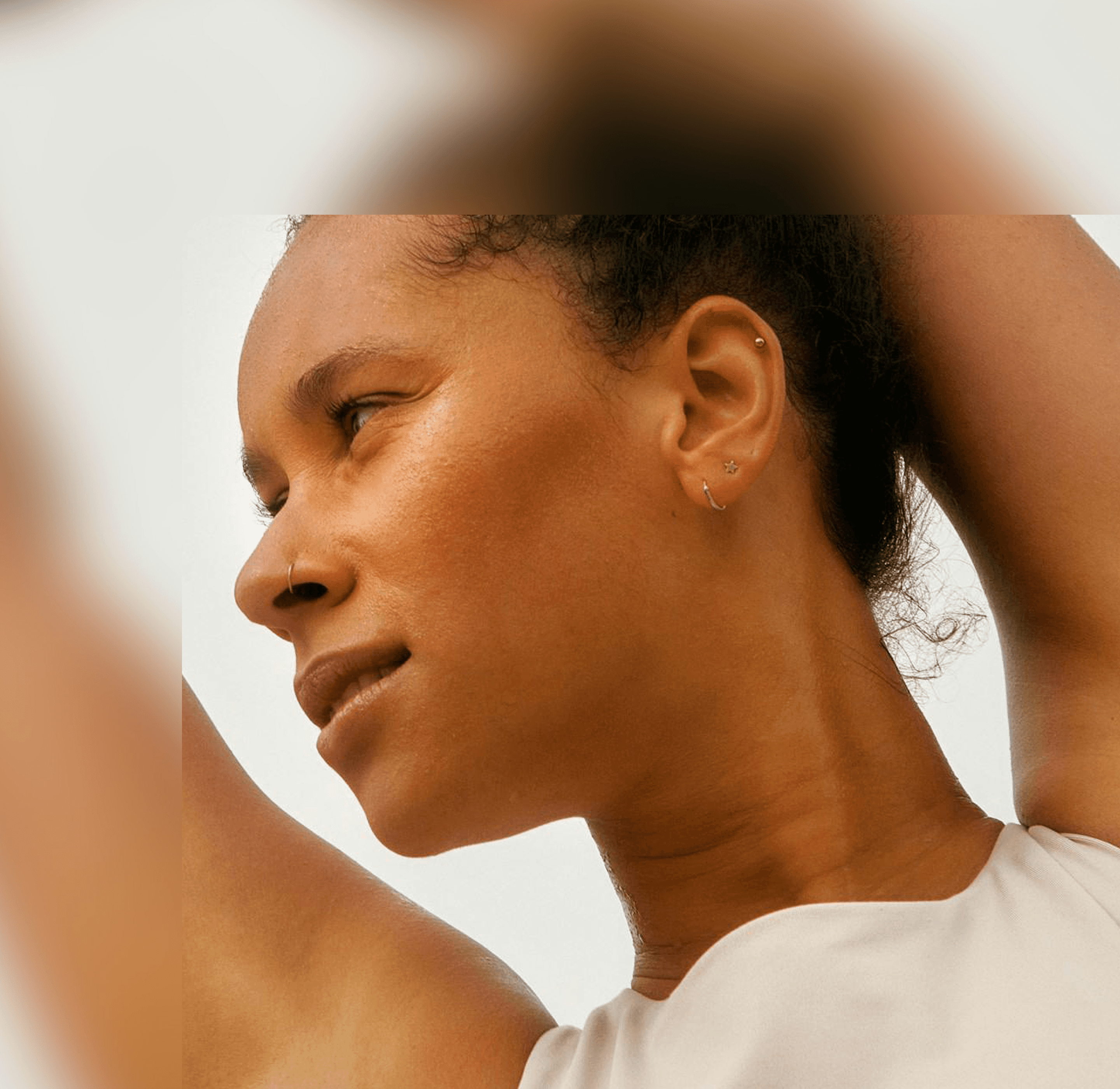 Portrait of a woman stretching her arms, softly lit, conveying calm, vitality, and wellbeing.
