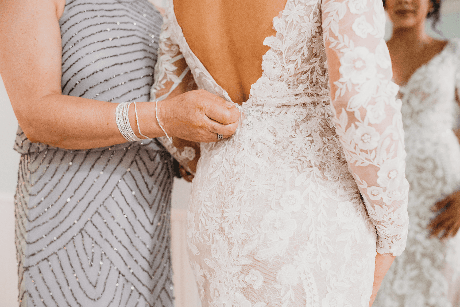 Mother of the bride zipping wedding dress and helping with veil