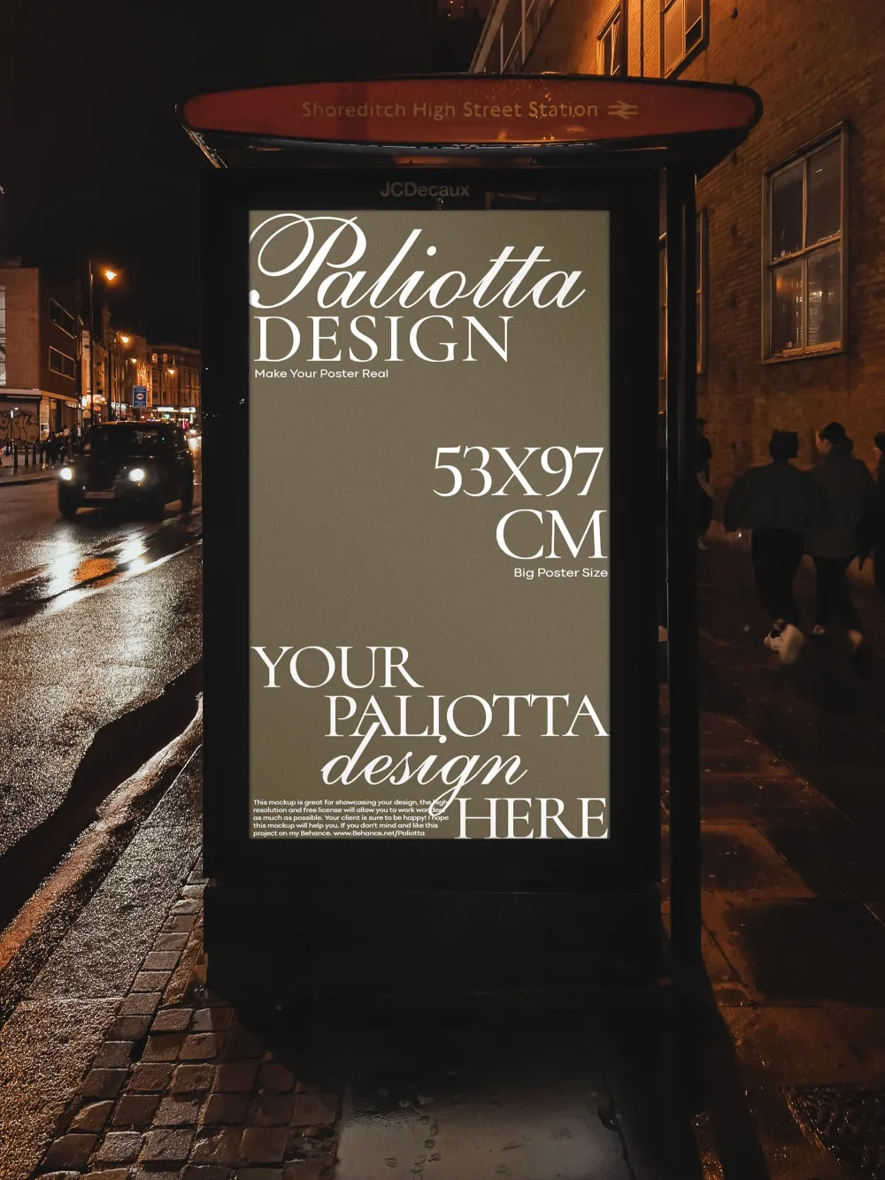 Backlit bus stop poster mockup at night near Shoreditch High Street Station, featuring a minimal black-and-white design. Wet pavement and warm streetlights create a moody urban ambiance.
