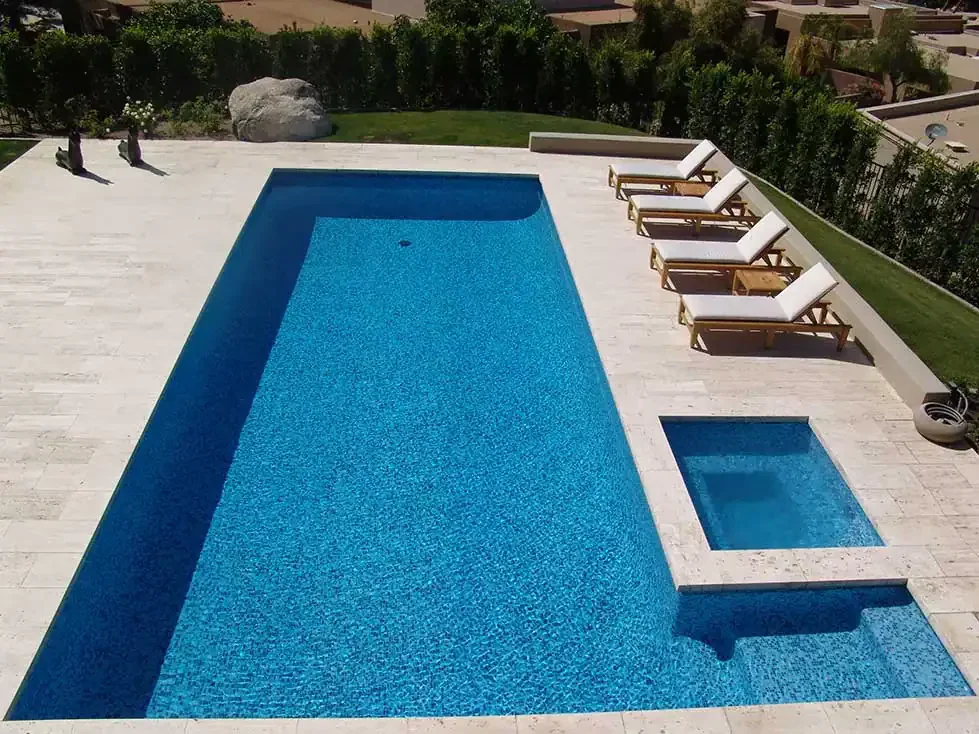 Swimming pool with lounge chairs in a modern backyard setting.