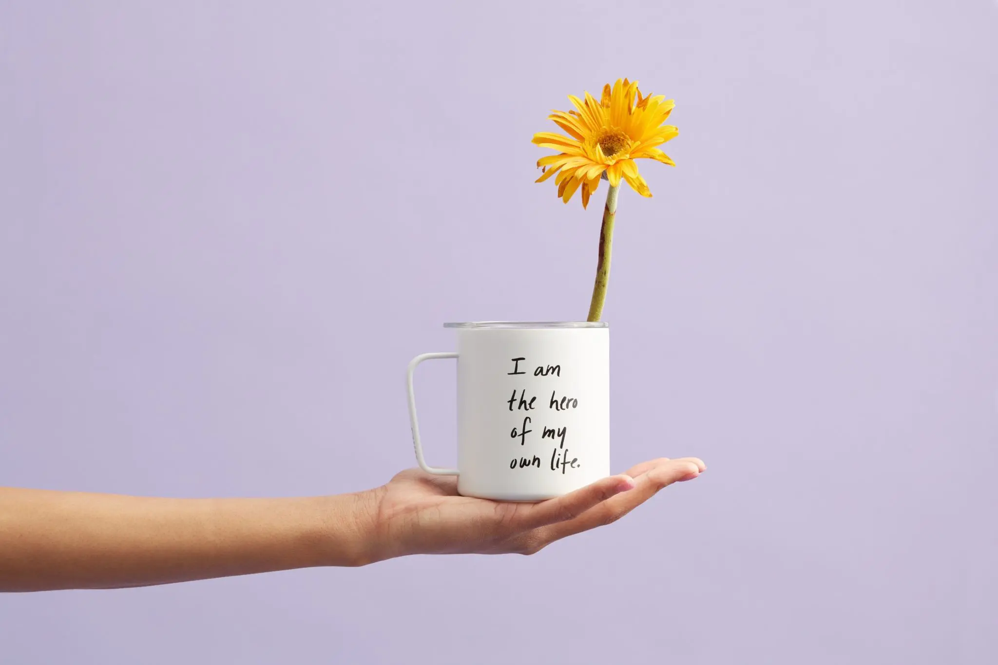 A mug with posotive affirmations inscribed on it and a sunflower sticking out of it