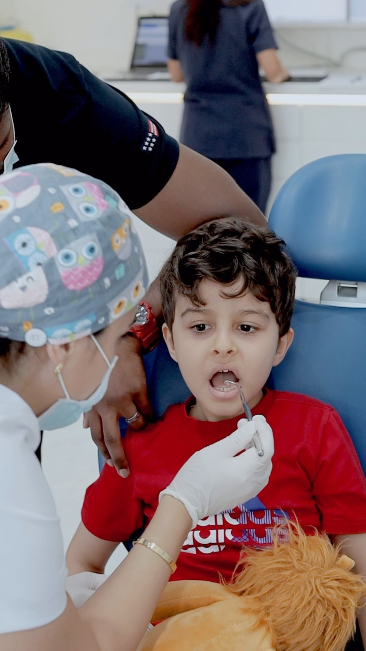 Pediatric dentist in Dubai at Invisalign Center with a parent checking a child’s teeth for issues during their appointment.