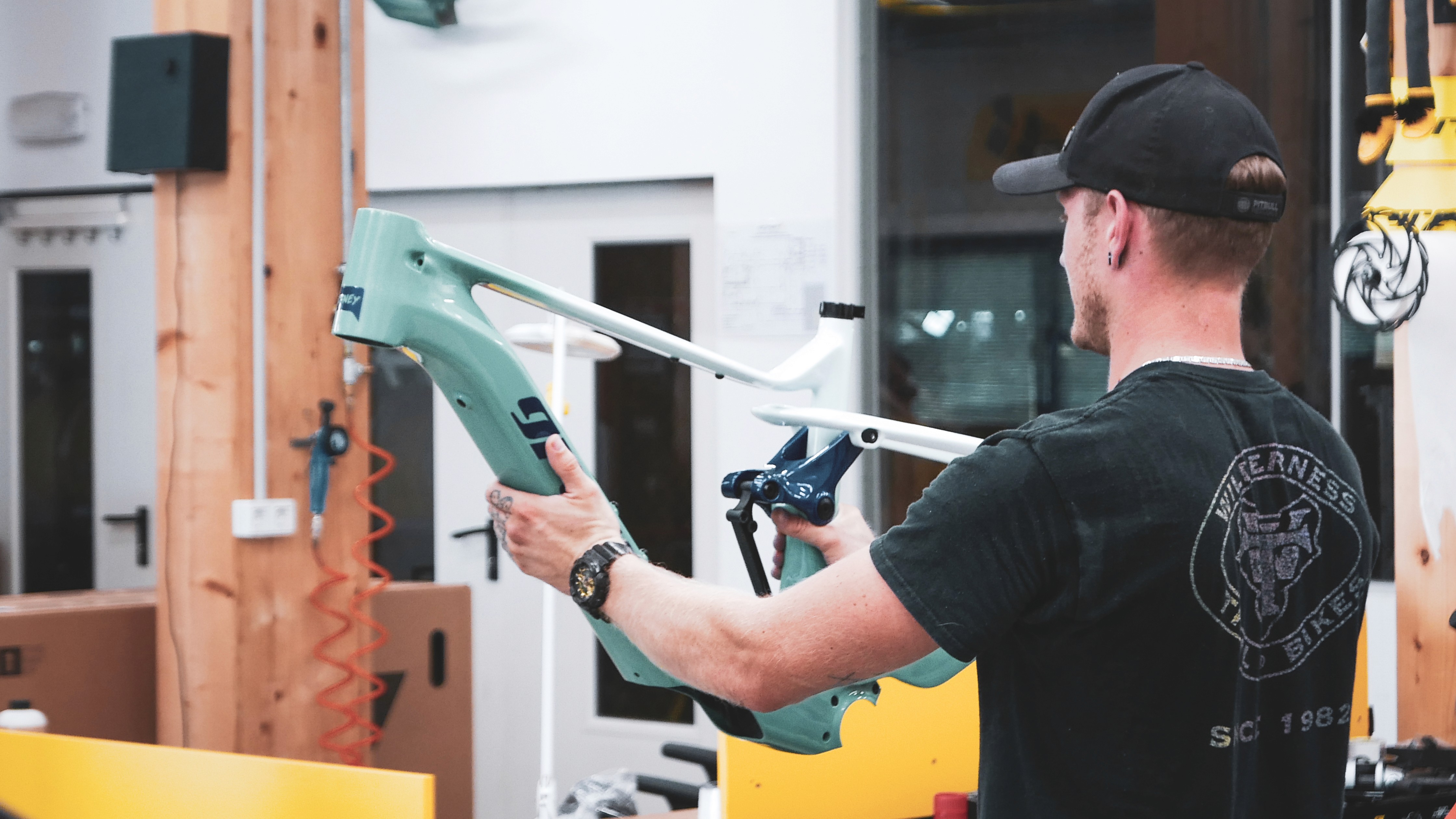 Man in garage holding an aluminum bike frame prototype.