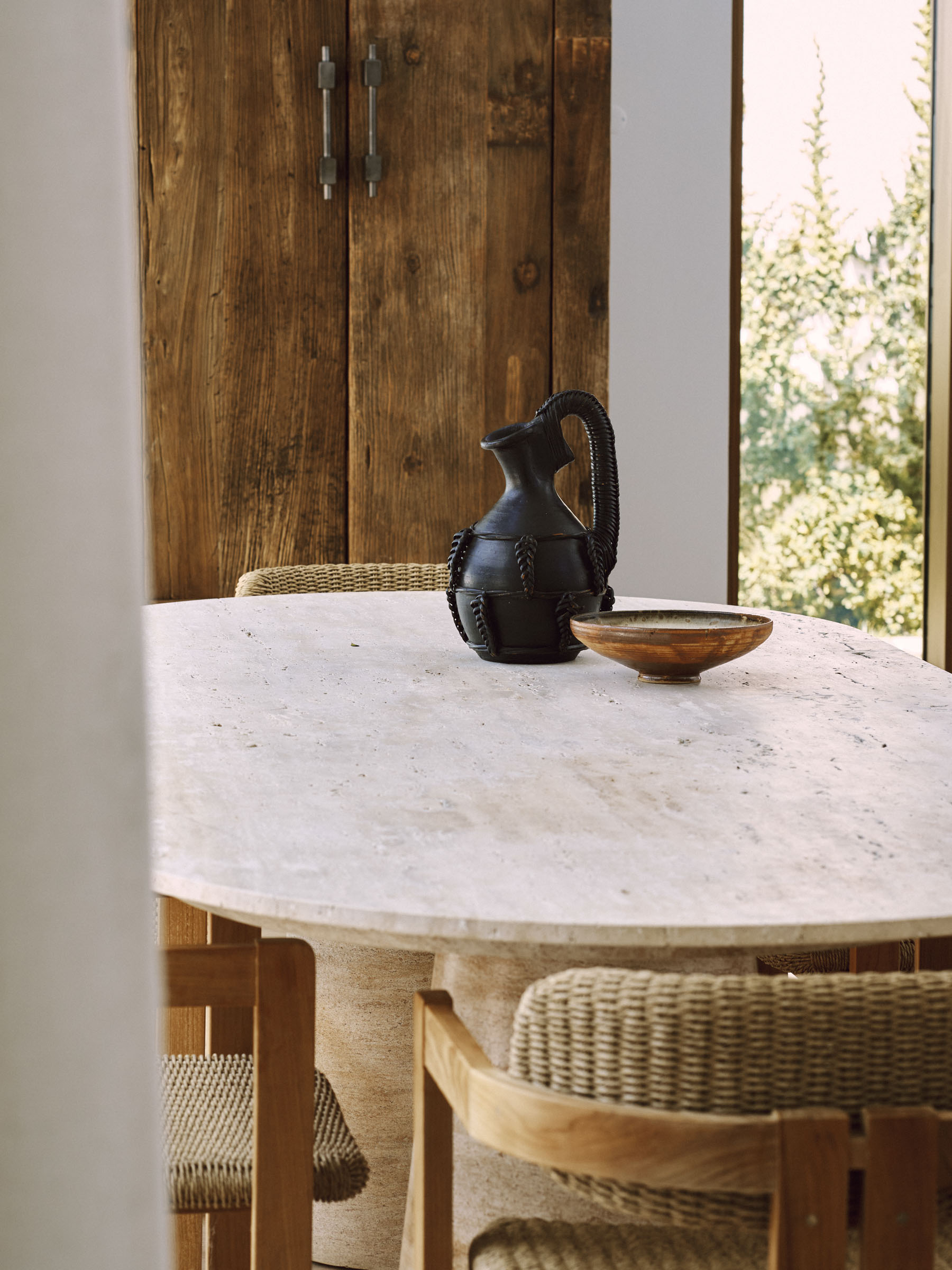 Dining table with ceramic objects and woven chairs in an Estoril house by Raúl Martins