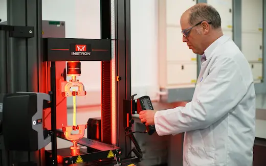 A photo of a lab scientist using a materials testing machine