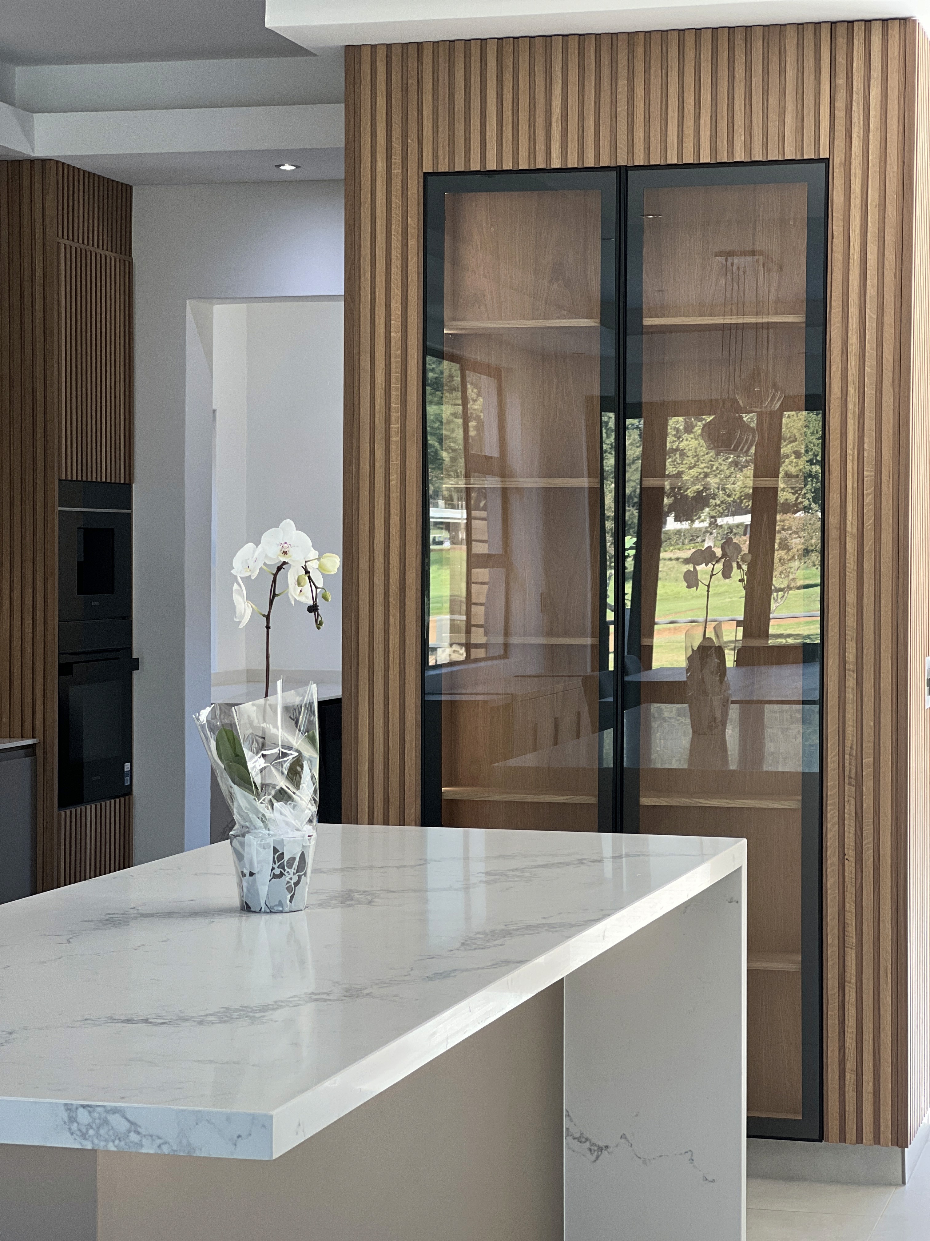 Modern timber-clad residence with horizontal wood facade and geometric volumes set on manicured lawn