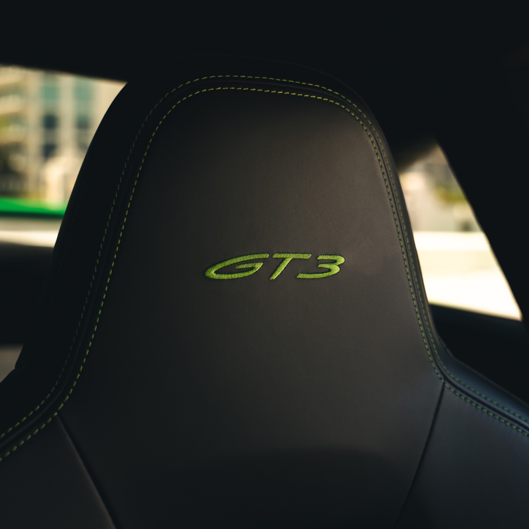 Close-up of Porsche 911 GT3 sport seat headrest with embroidered GT3 logo, luxury performance details.