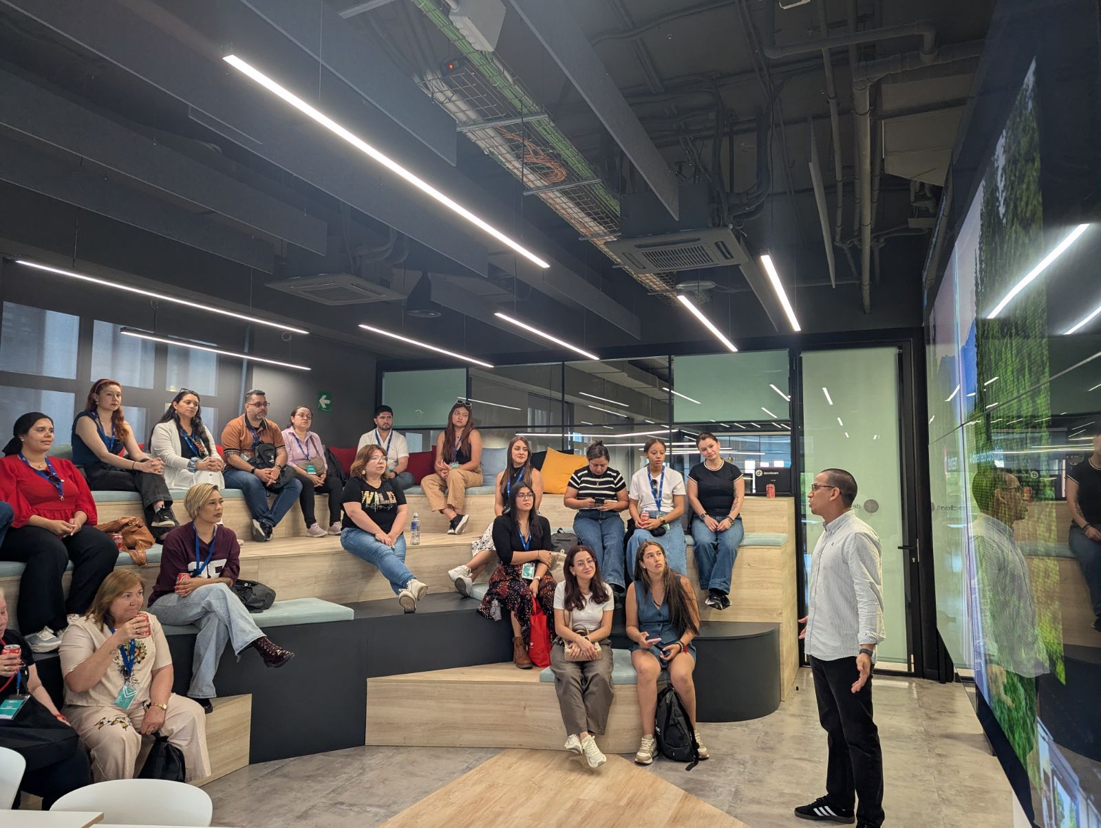 Two men standing together, one holding a tablet and showing it to the other as they both smile.