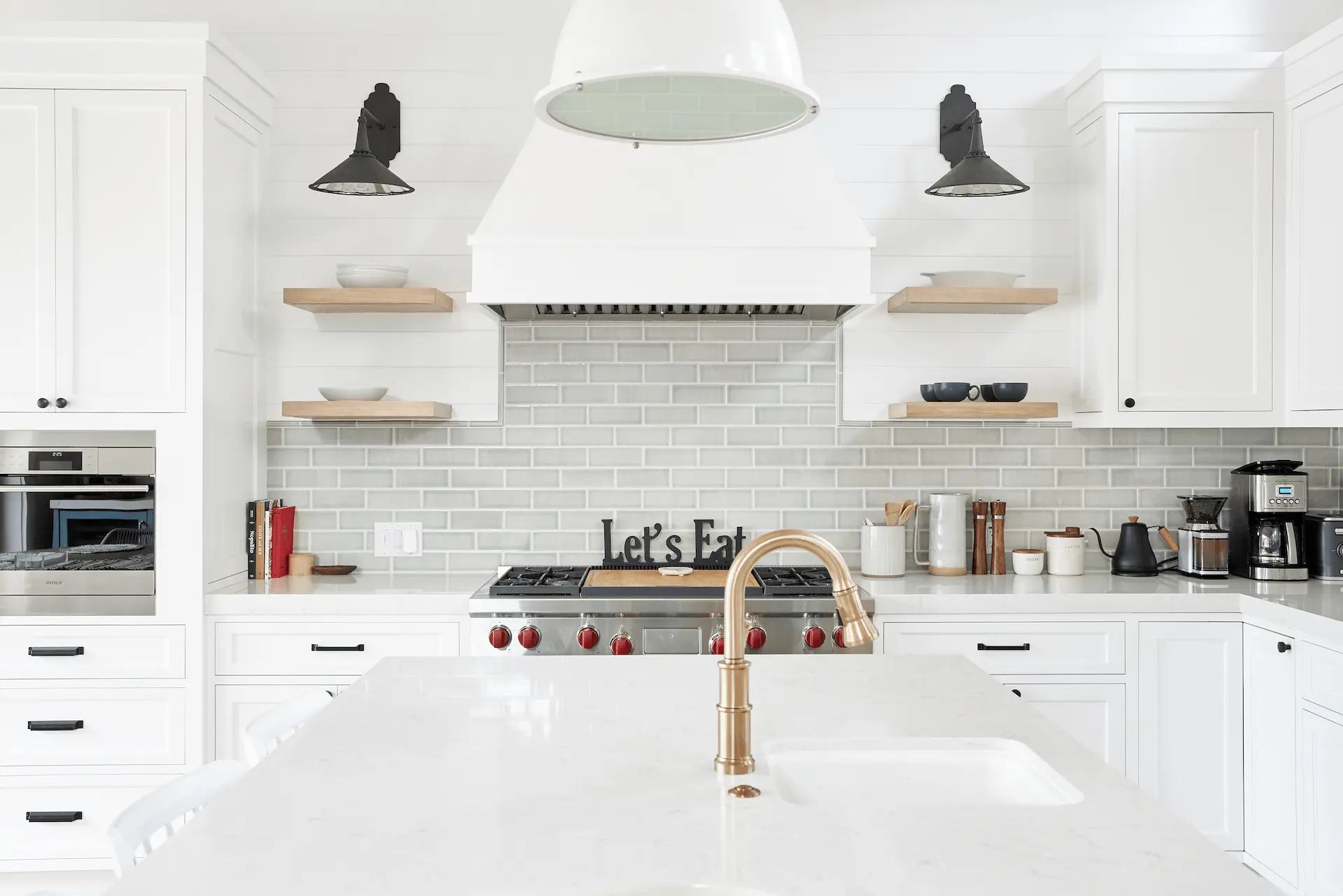 Sleek kitchen with white quartz island, brass fixtures, and black accents in North Tustin Remodel & Addition. Photo by Todd Huge.