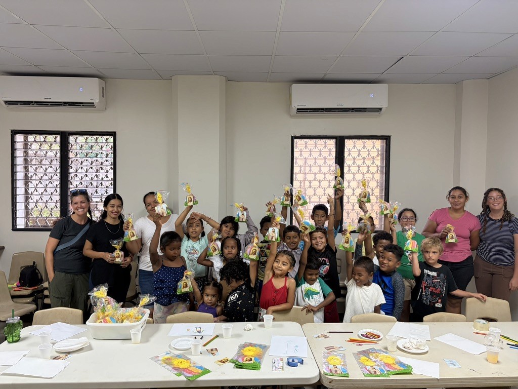 Adults and children holding crafts during a church youth activity.