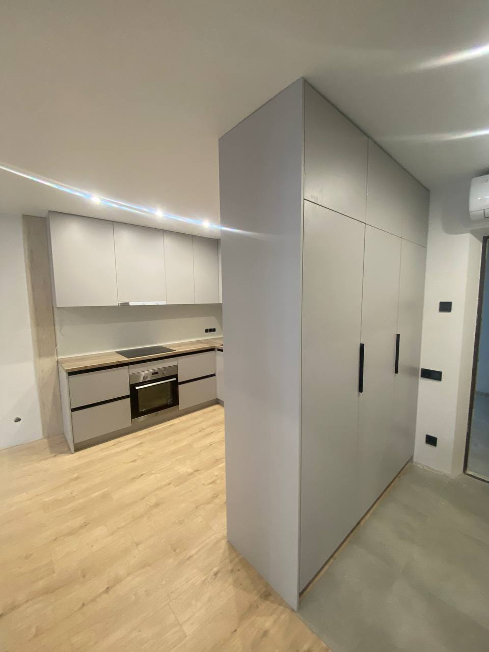 Світла кухня з дерев’яною стільницею та підсвіткою фасадів