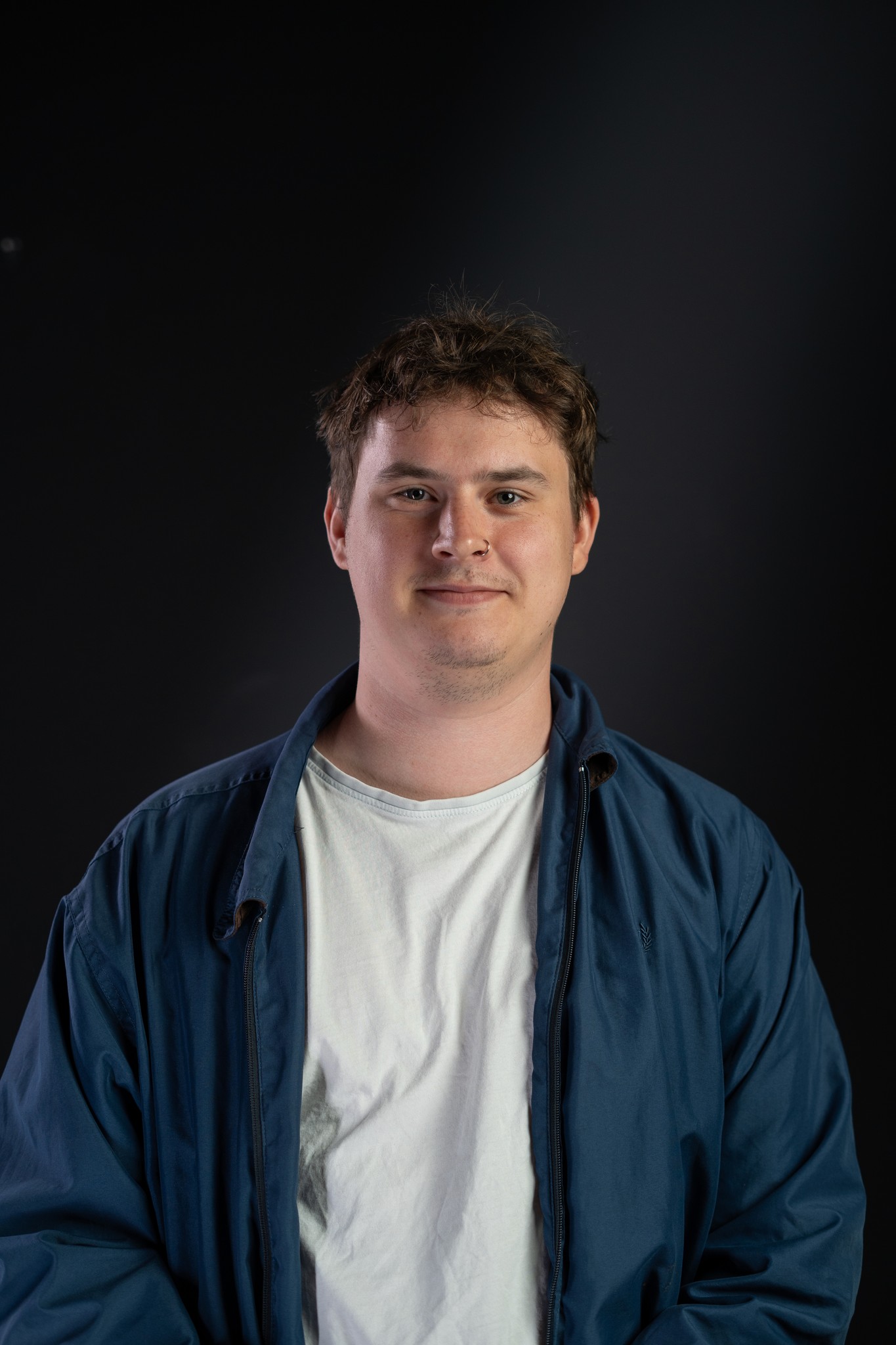 A model wearing an elegant cream blazer sits on a chair against a bright blue background, showcasing a modern and minimalist professional style.