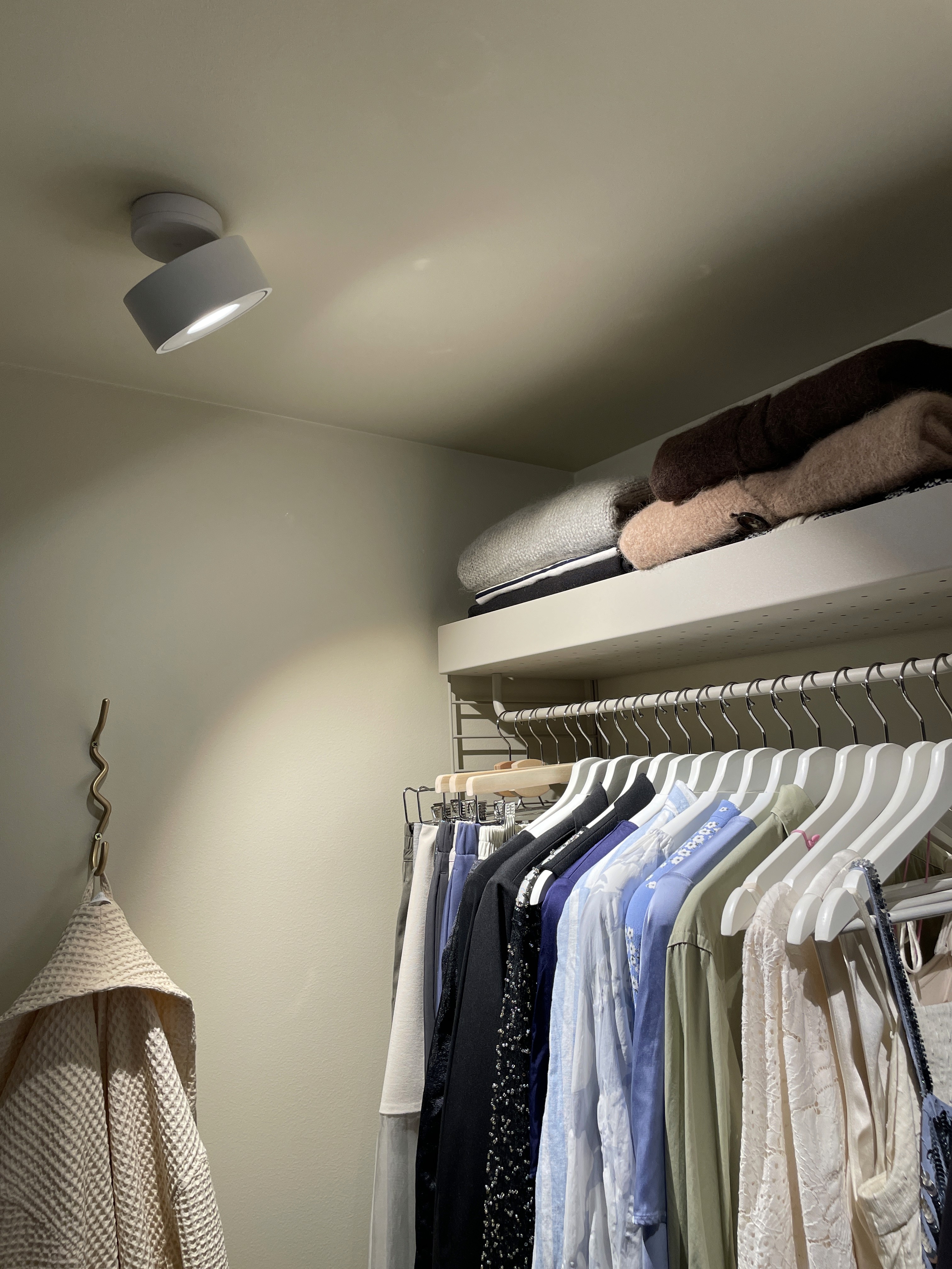 Open wardrobe with clothes rails and ceiling lighting in the small Oslo studio apartment.
