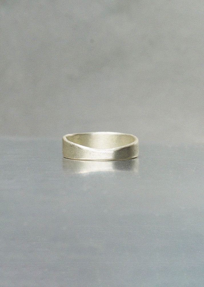 Silver ring on a reflective gray surface with a neutral background