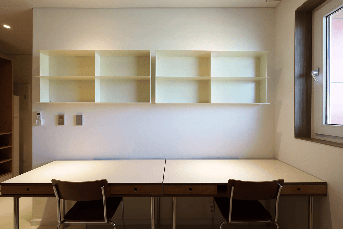 Work corner of a single room at Mangrove Sinseol with a wooden desk and an orange chair.