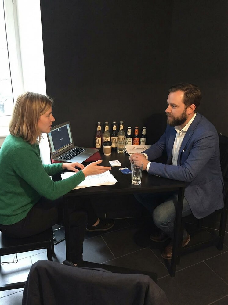 Photo of a usability testing session with a merchant seated at a table, reviewing a debit card experience while discussing tasks and feedback with a researcher.