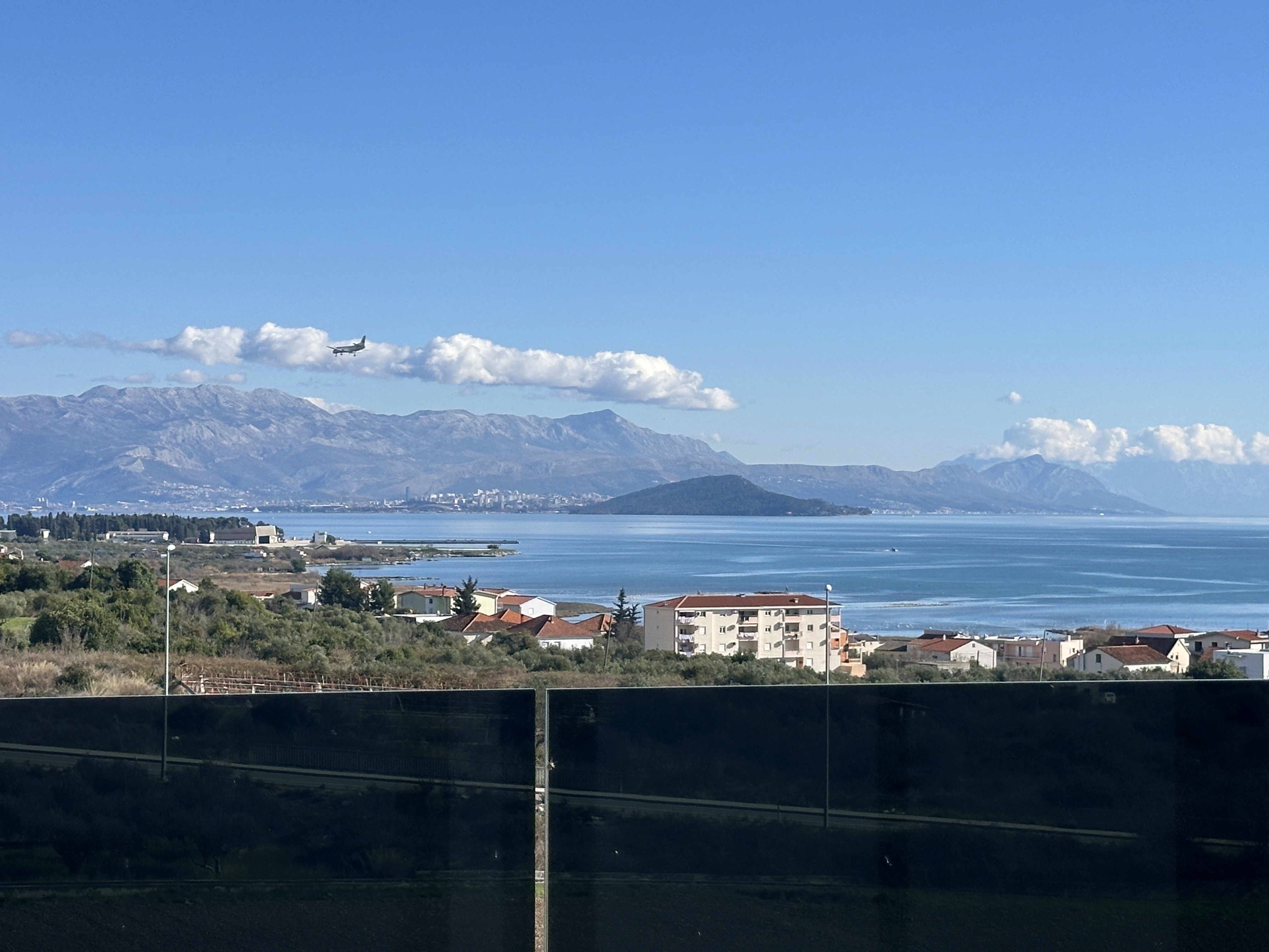 Modern white building with curved glass and reflecting pool.
