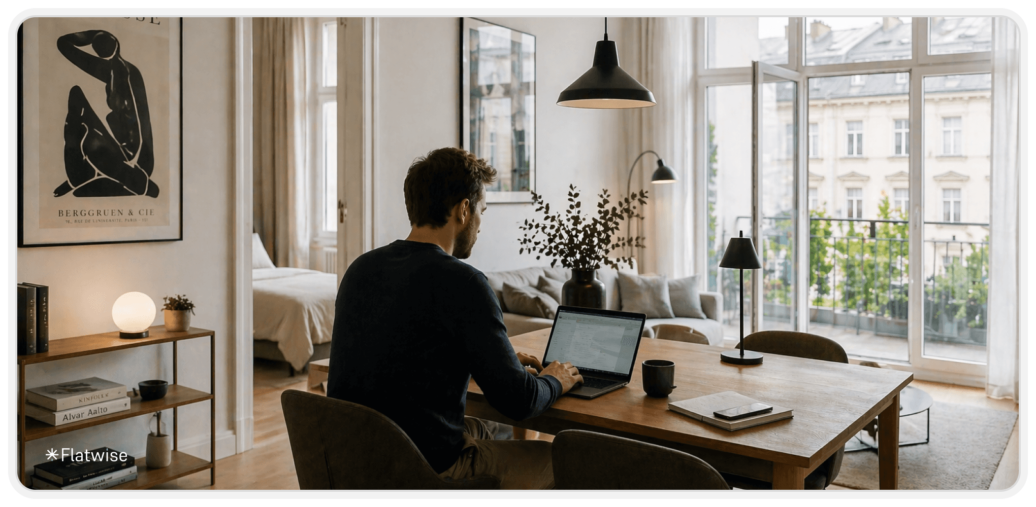Moderner Wohnbereich einer Wohnung, in dem ein Geschäftsmann am Esstisch sitzt und konzentriert an seinem Laptop arbeitet, mit viel Tageslicht und minimalistischem Interior.