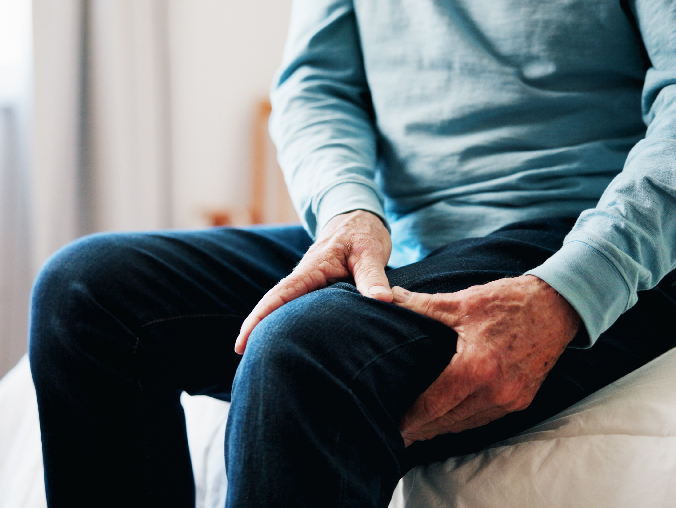 older man holding his sore leg after using his stationary bike to lose weight too intensely