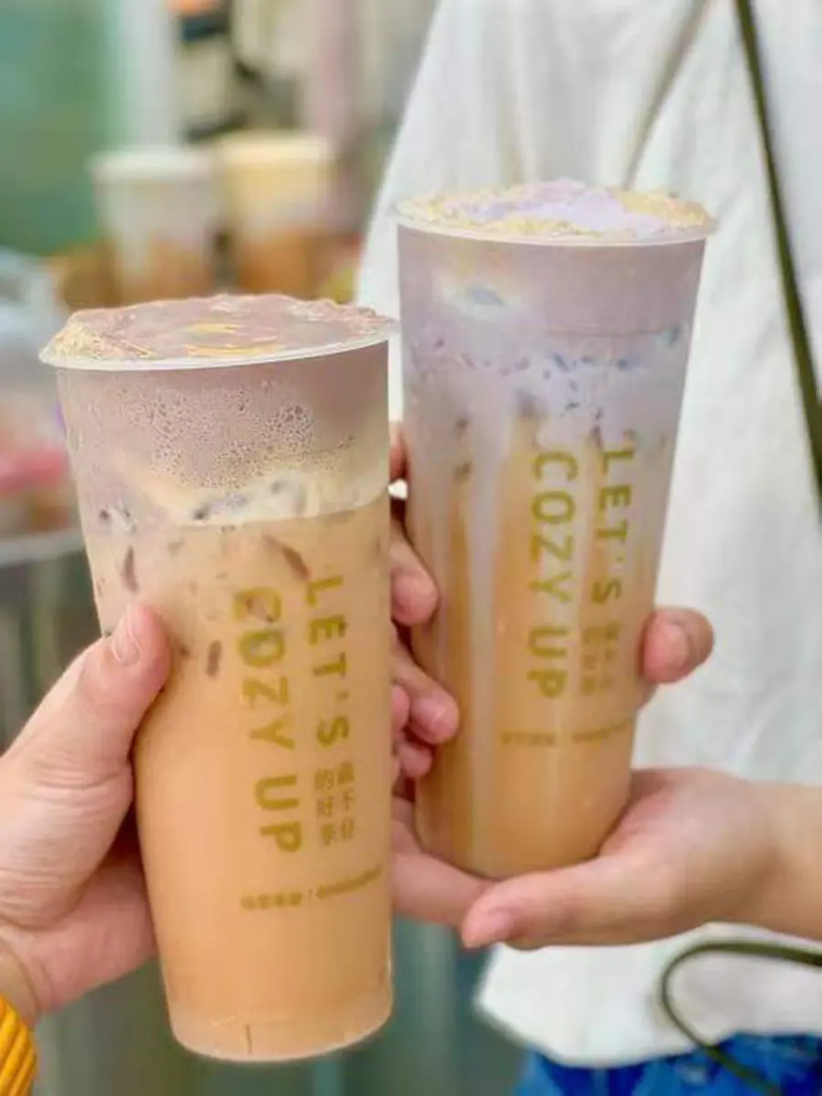 Two freshly made bubble teas held by a customer, featuring Cozy Tea Loft’s signature drinks with visible tapioca pearls, highlighting their authentic Taiwanese tea offerings.