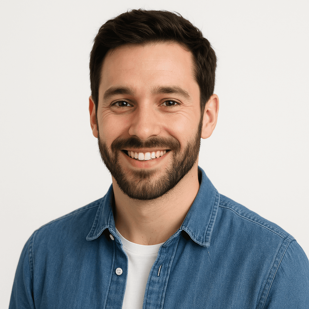 Smiling man with dark hair and beard wearing a blue denim shirt. He appears friendly and approachable.