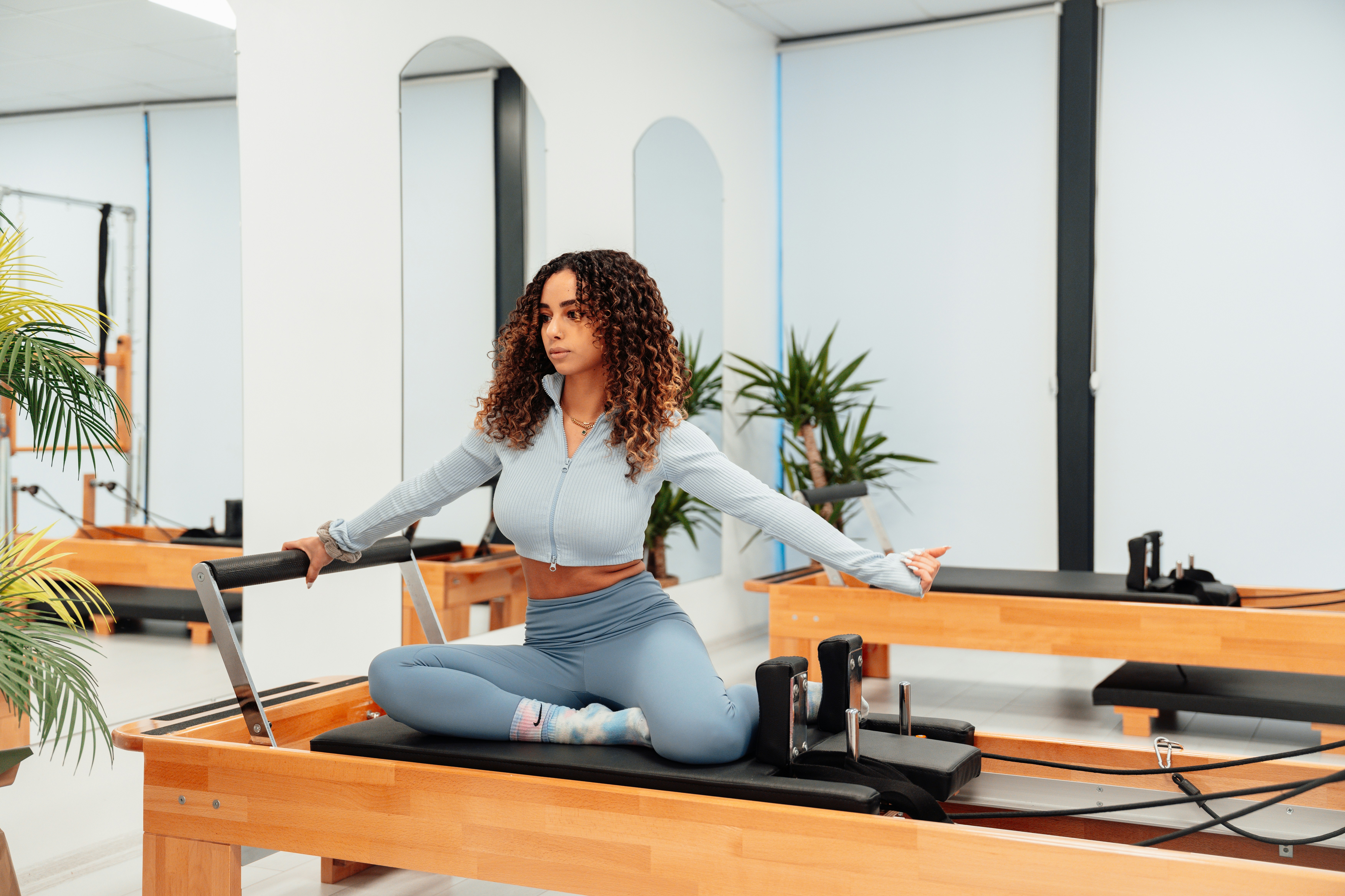 a woman sitting on a pilates reformer in a gym