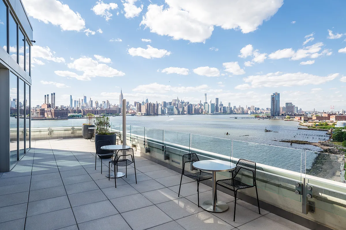 A balcony with a scenic view of the city and water, showcasing urban architecture and natural beauty.