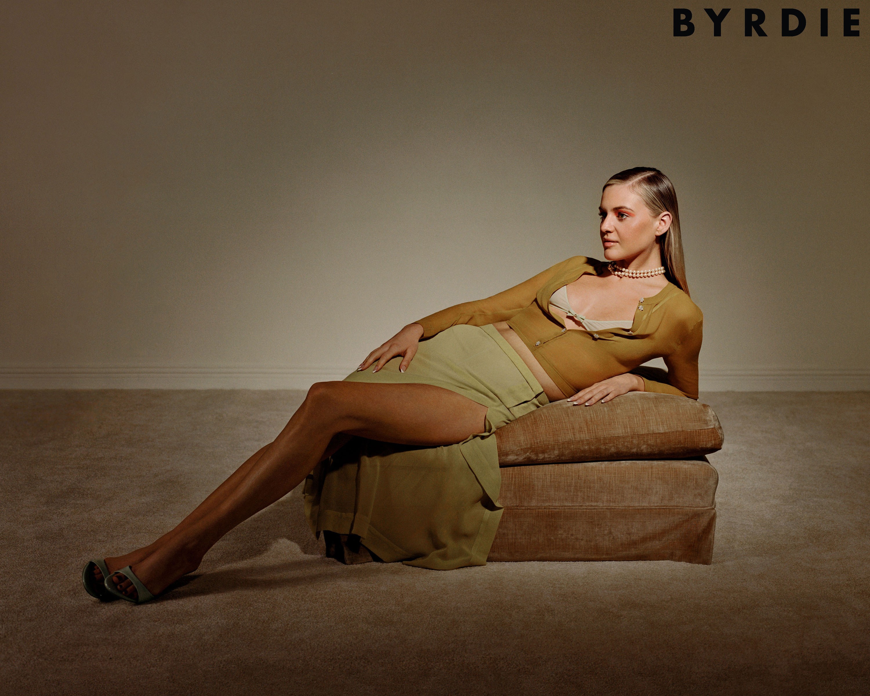 Kelsea Ballerini reclining on a green ottoman